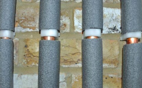 Foam pipe insulation wrapped around copper pipes in crawl space