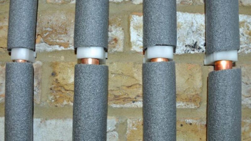 Foam pipe insulation wrapped around copper pipes in crawl space