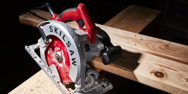 Close-up of a cordless circular saw mid-cut on plywood, showcasing blade depth adjustment.