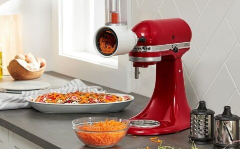 KitchenAid mixer with slicer attachment slicing fresh vegetables on a countertop.