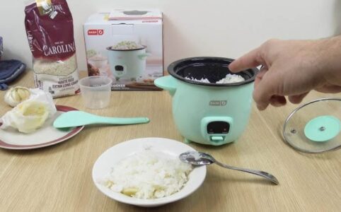 Dash mini rice cooker on kitchen counter with steaming rice