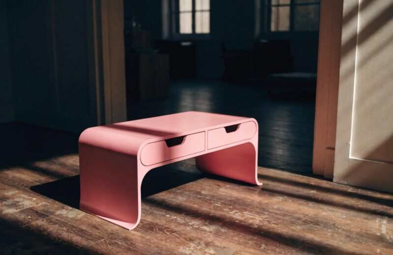 Small console table with drawers in pink styled in a modern entryway with mirror and decorative accents